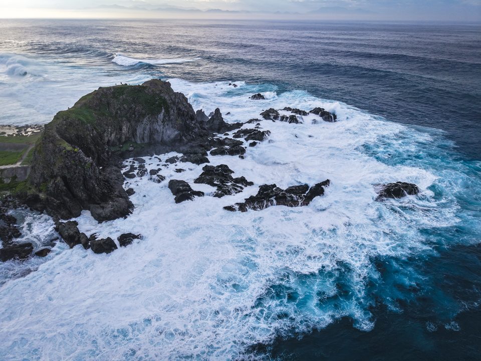 綠島公館鼻的空拍畫面，草坡與海岬延伸入海