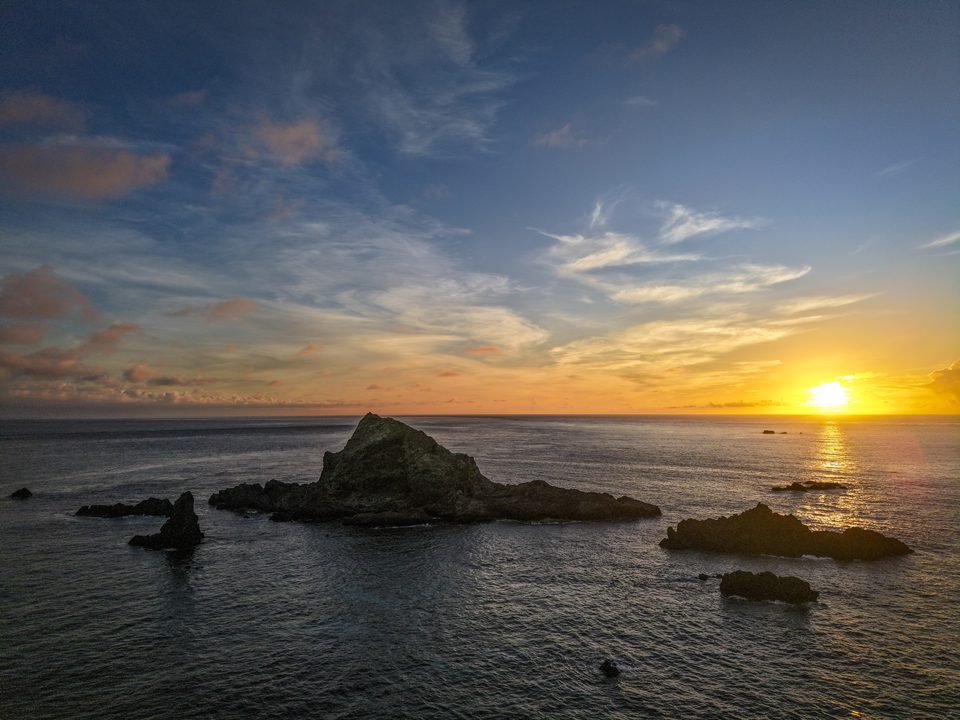 綠島樓門岩的空拍畫面，海蝕拱門矗立在深藍色海面上